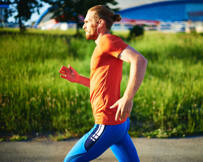 A man with a bun, wearing orange shirt and blue running leggings, jogging, representing neighbor running stalker. A man with a bun, wearing orange shirt and blue running leggings, jogging, representing neighbor running stalker.