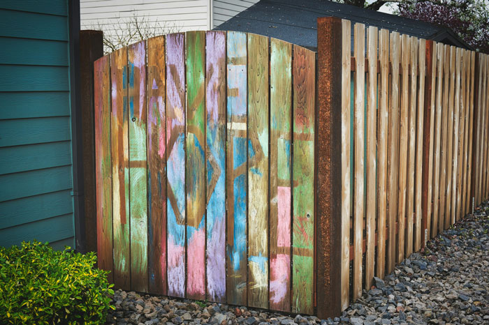 Wooden fence with colorful graffiti damage neighbor fence conflict
