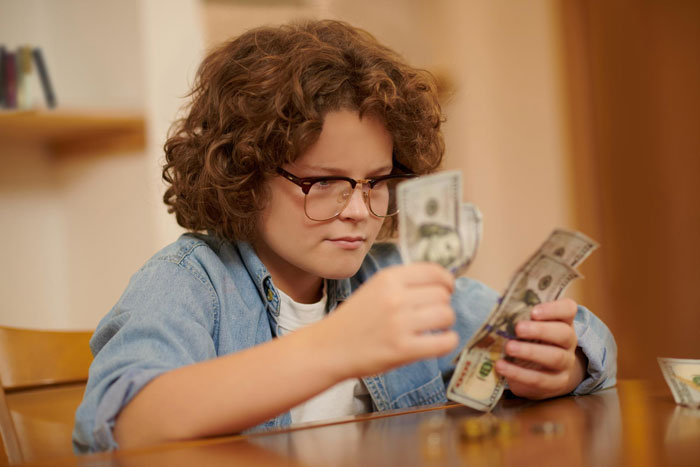 Child counting money at table after fence damage conflict