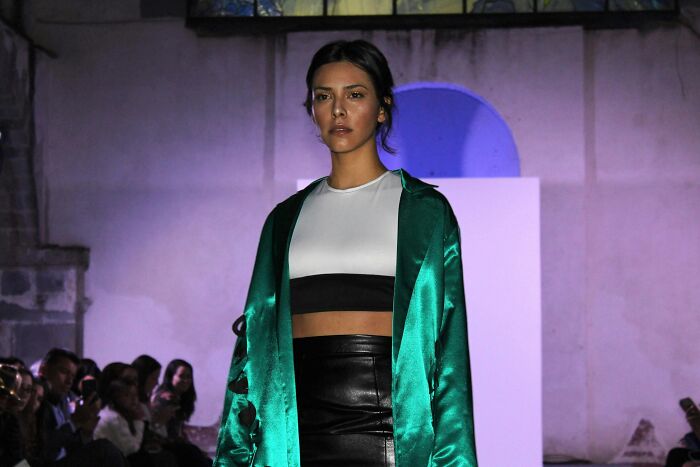 Model walking runway wearing green coat at January 6 fashion event
