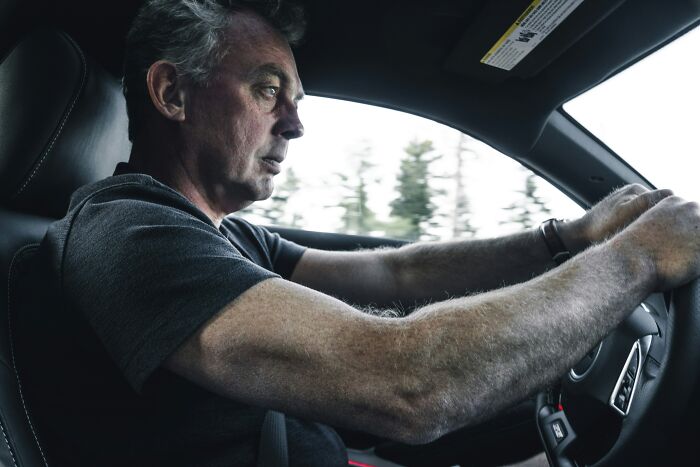 A man driving, focusing intently on the road, contemplating if patients are alive right now, hinting at extraordinary survival stories.