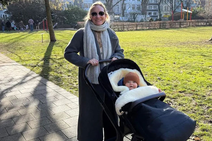 Woman pushing baby stroller outdoors in Germany with full paid maternity leave Woman pushing baby stroller outdoors in Germany with full paid maternity leave