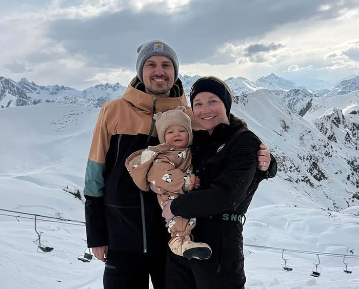 Family posing with baby in snowy mountains highlighting Germany maternity benefits Family posing with baby in snowy mountains highlighting Germany maternity benefits