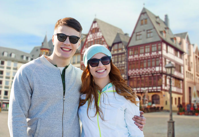 Couple smiling in front of traditional German buildings on a sunny day Couple smiling in front of traditional German buildings on a sunny day