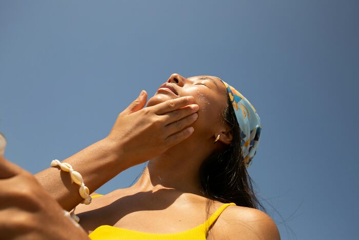 Woman applying sunscreen under clear blue sky for shocking facts