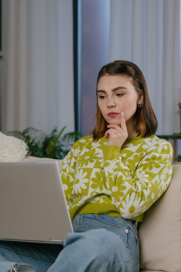 A thoughtful woman on a laptop, reading or watching wedding drama stories.