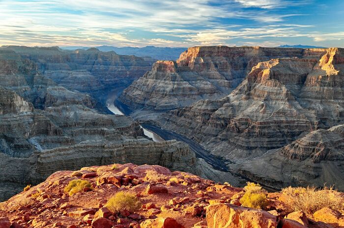 A breathtaking Grand Canyon vista at sunset, with a river winding through the vast, layered landscape. Engagement stories and chaos.