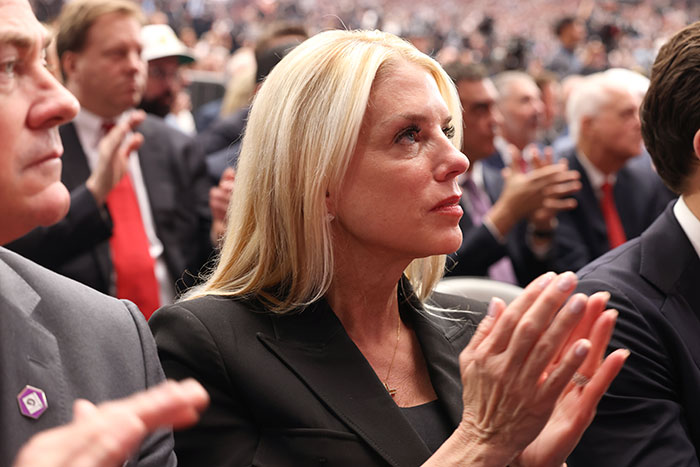 Pam Bondi in black outfit clapping at a public event