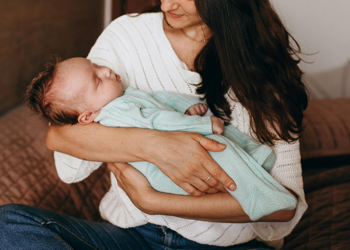 Mother holding sleeping baby in arms for looksmaxxing care