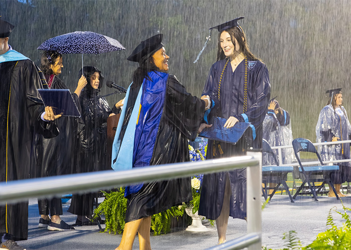 High school graduation ceremony in pouring rain with graduate receiving diploma High school graduation ceremony in pouring rain with graduate receiving diploma
