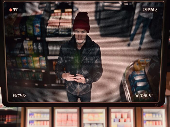 CCTV footage showing a man in a red beanie and plaid jacket holding a small plant in a store. Lawyers defend impossible cases.