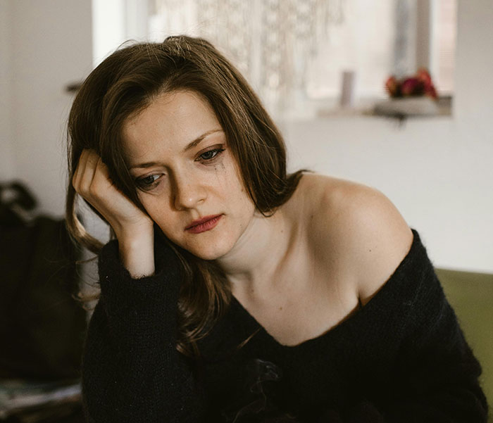 Pensive woman resting head on hand, showing emotions from cheating stories