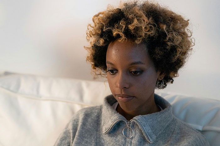 Sad woman on couch thinking deeply about ugly cheating stories