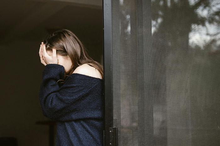 Upset woman covering face, depicting pain from cheating stories