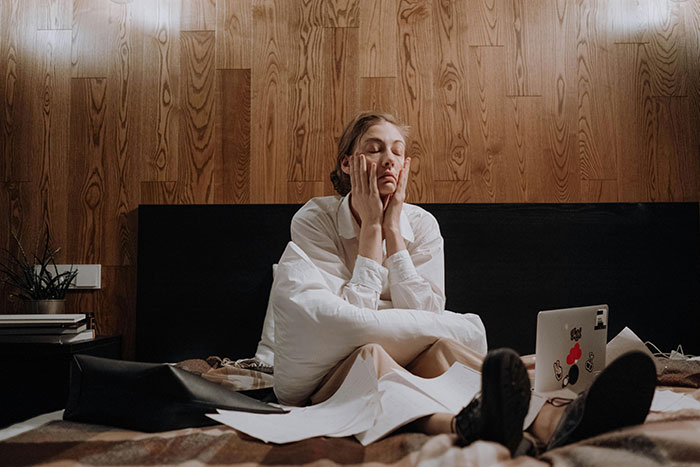 Depressed woman in bed with laptop overwhelmed by cheating stories