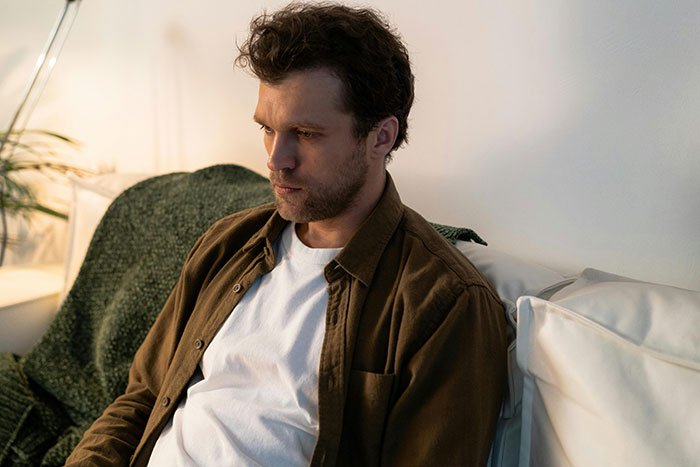 Pensive man sitting alone reflecting on cheating and relationship issues