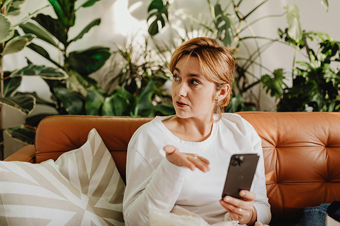 Woman frustrated holding phone on couch symbolizing ugly cheating stories