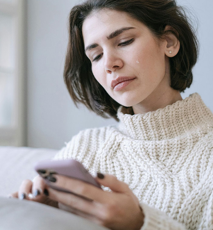Crying woman looking at phone during cheating story revelation