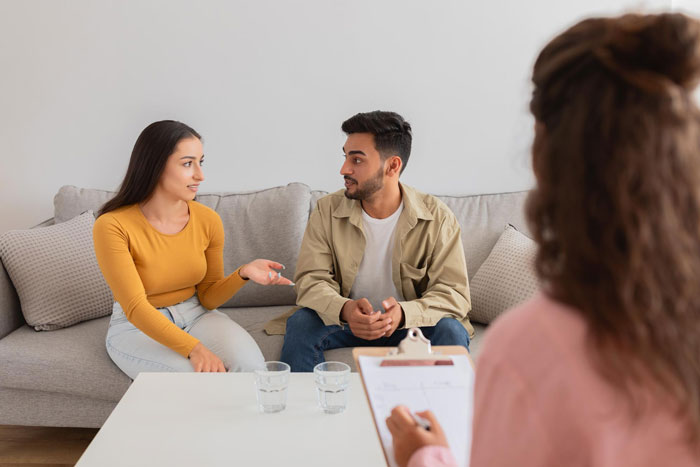 Couple in therapy session discussing paternity test and marital issues on couch Couple in therapy session discussing paternity test and marital issues on couch