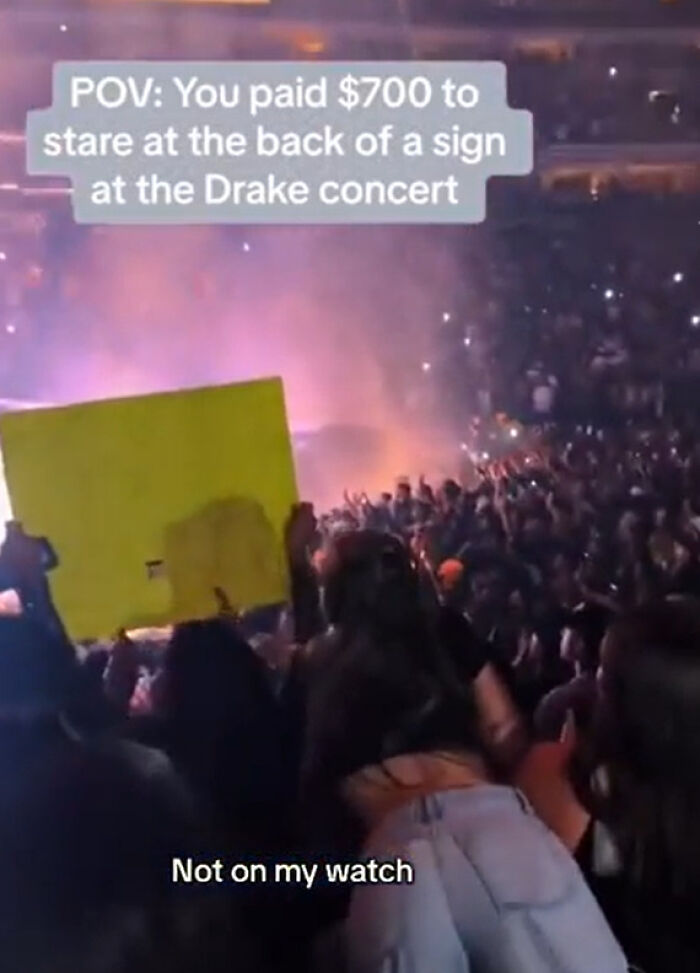 Concert crowd with person holding a sign back facing the stage
