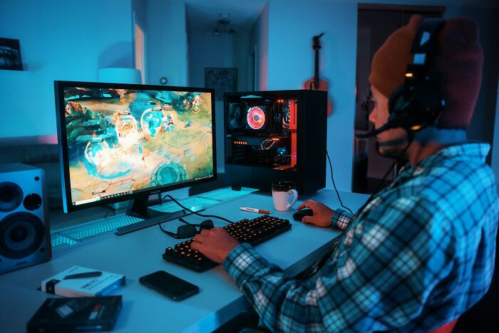 Person gaming on computer at night with gaming setup and headset