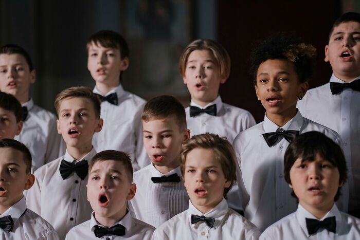 Young boys in white shirts and black bow ties singing in a choir, showcasing fun facts from their expertise.