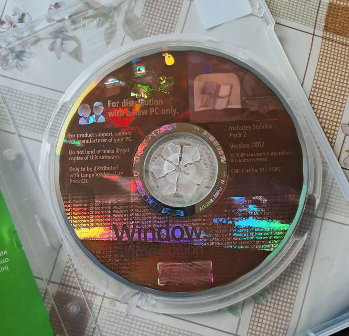 A reflective Windows XP CD in its case, showcasing fun facts about past operating systems.