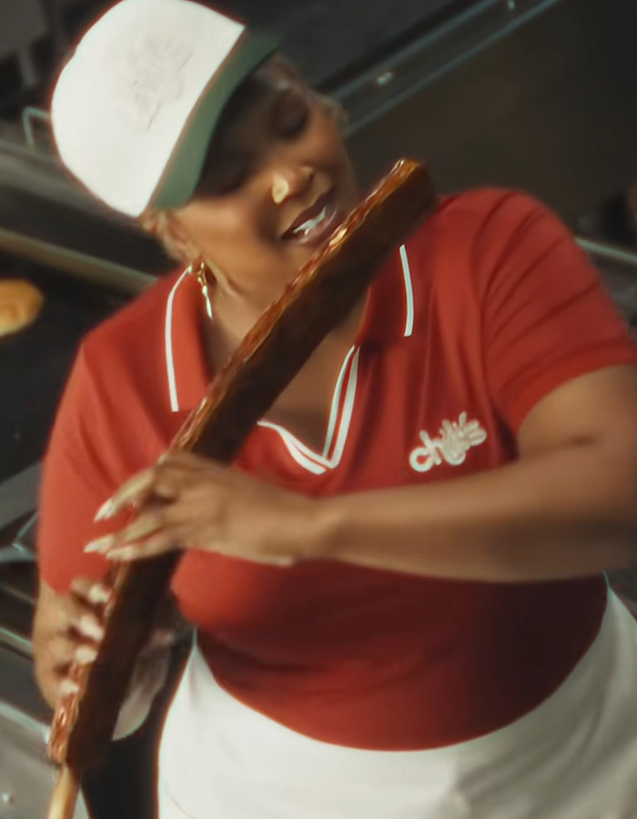 Lizzo playfully holding a large rack of ribs in Chilis uniform Lizzo playfully holding a large rack of ribs in Chilis uniform