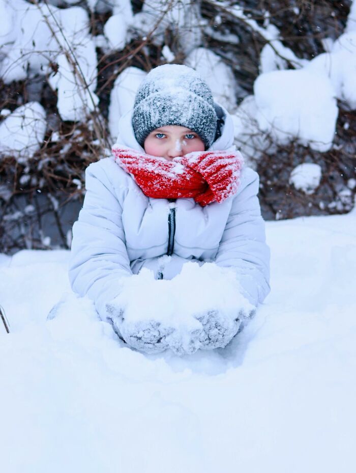 Child playing with snow wearing winter clothing