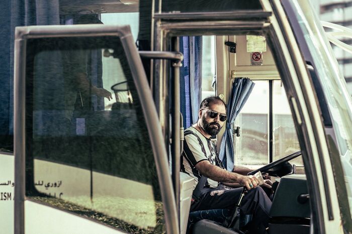Focused bus driver sitting in vehicle cabin wearing sunglasses