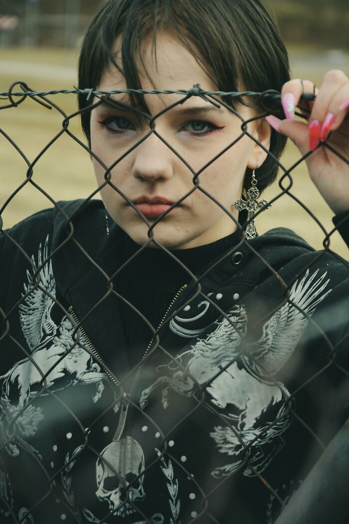 Teen girl behind fence with cross earring depicting life after cult escape