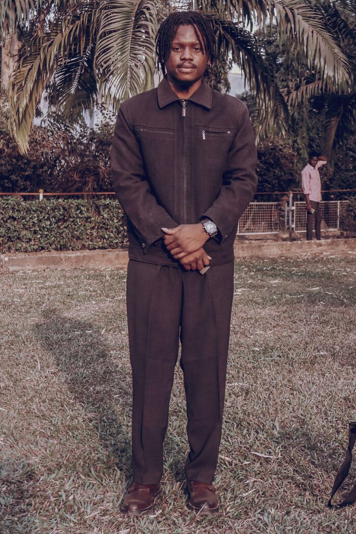Man standing outdoors dressed in brown outfit near palm trees