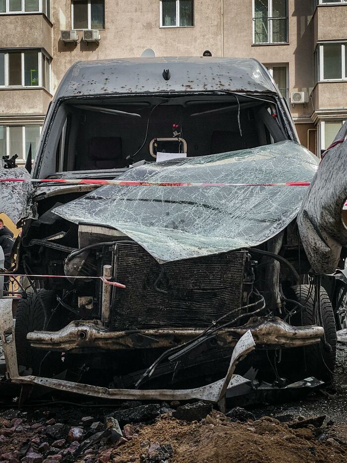 A heavily damaged vehicle, its front crushed and windshield shattered, resembling a glitch in the Matrix.