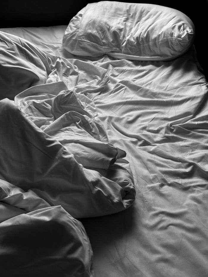 Unmade bed with rumpled sheets and pillow in monochrome