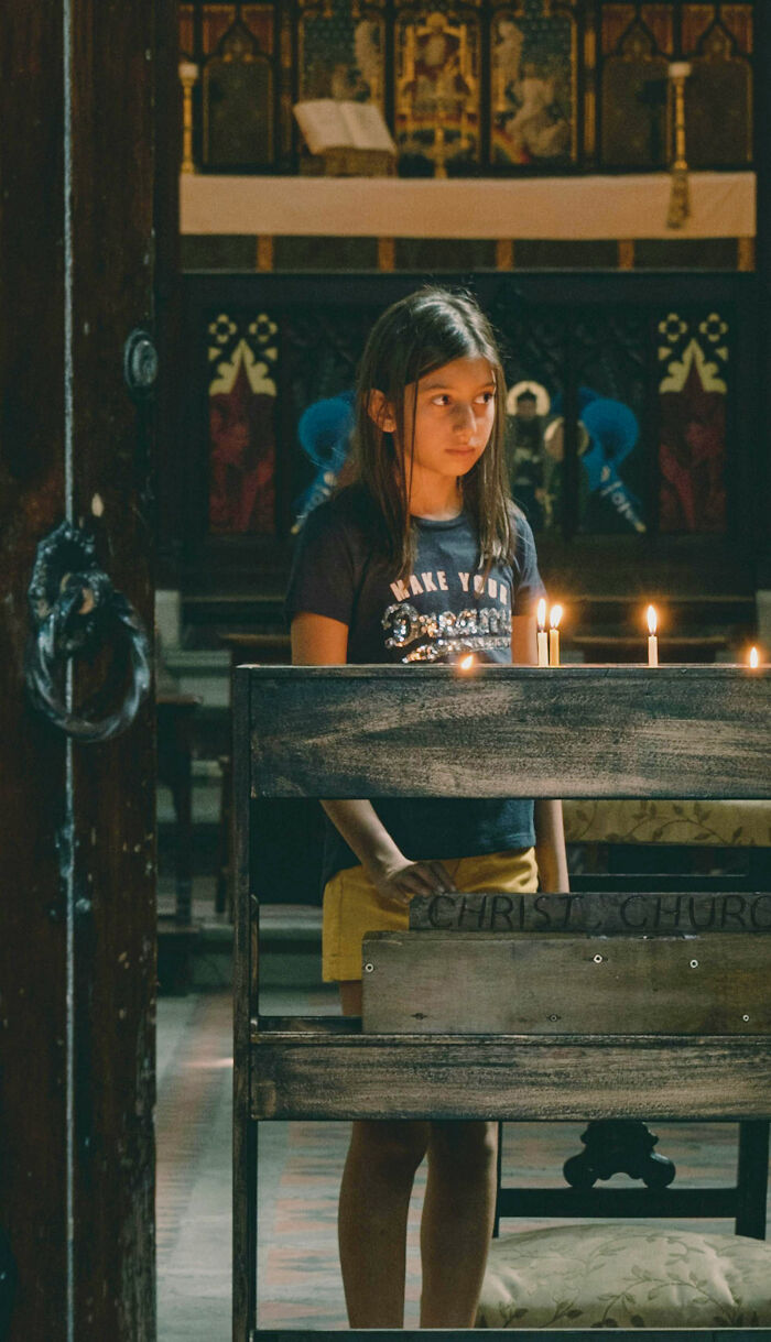 Child standing near candles in church reflecting on cult escape moments
