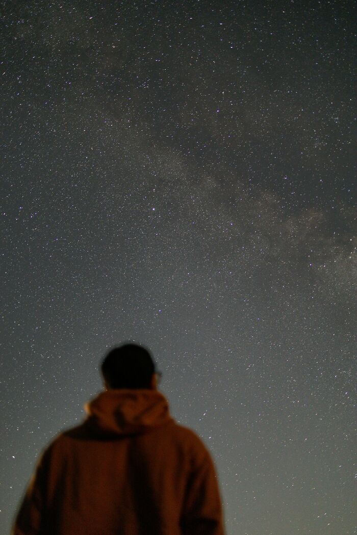 Person stargazing under clear night sky filled with stars