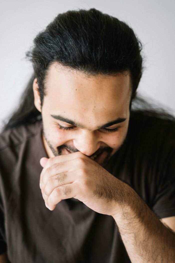 Man smiling and covering mouth looking down