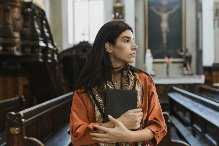 Woman holding Bible inside church looking away representing cult escape realization