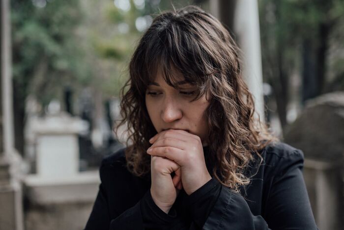 A pensive woman with hands clasped, highlighting the solemn or regrettable moments in wedding drama stories.
