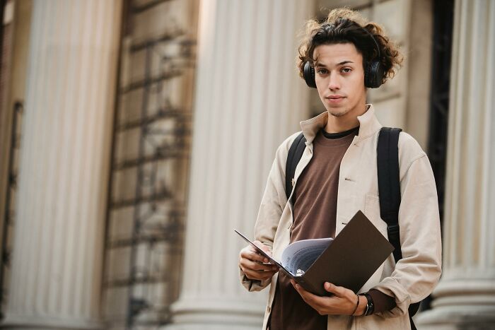 Young man listening to music with headphones and holding notebook