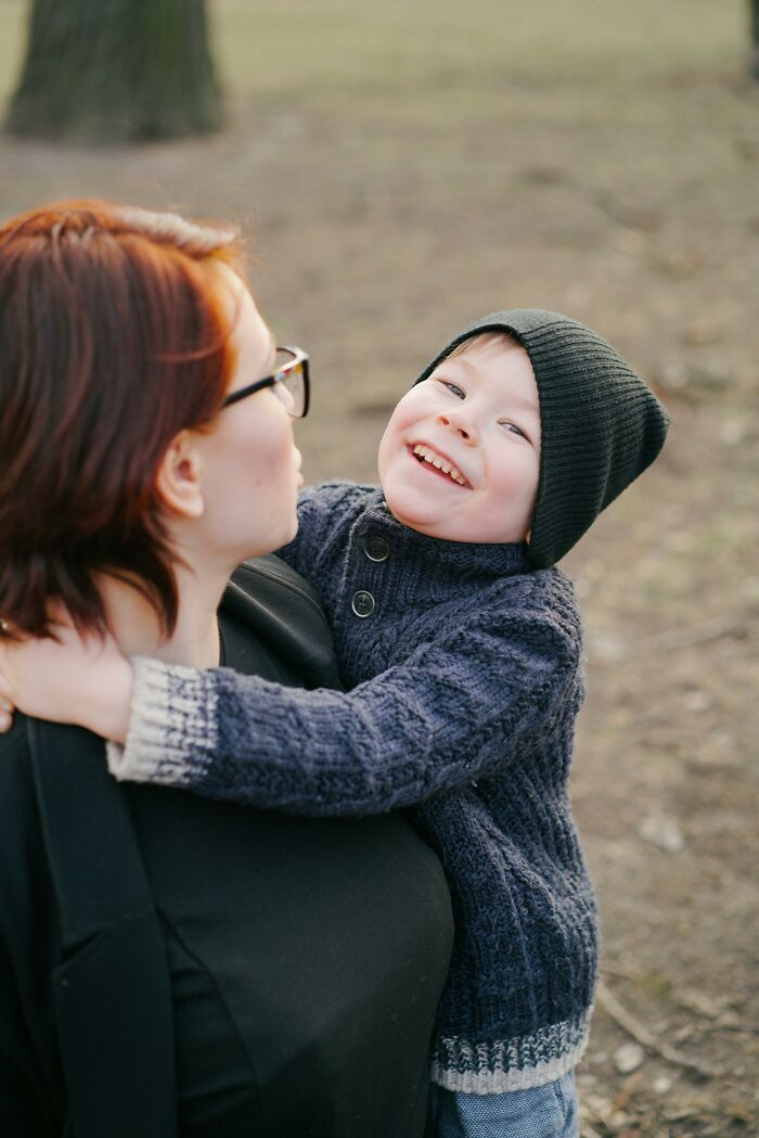 Smiling child hugging woman outdoors in cozy sweater