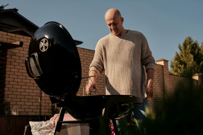 Man grilling food on barbecue in backyard on sunny day