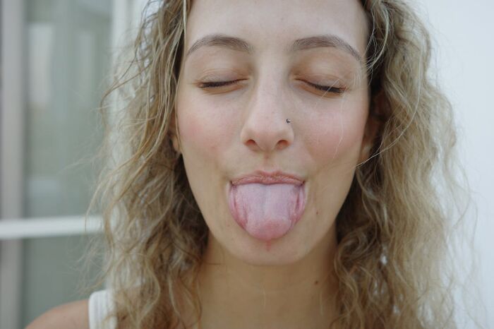 Young woman with curly hair sticking out her tongue playfully