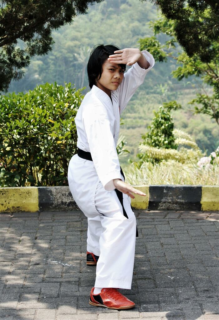 Person practicing martial arts outside wearing traditional gi and black belt