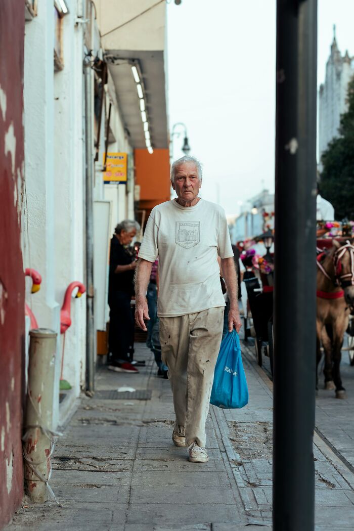 Older man walking on street carrying a reusable shopping bag