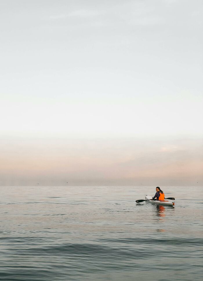 Woman on paddleboard in vast, calm ocean. The serene scene feels like one of the very creepy things that people experienced.