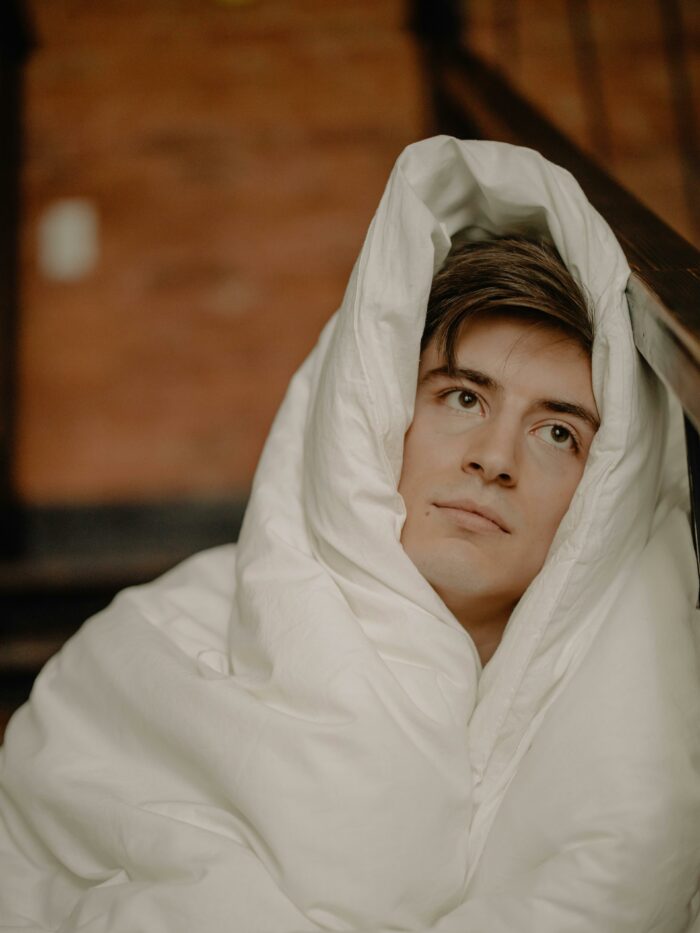 Young man wrapped in blanket looking thoughtful to prove a point to stepdad