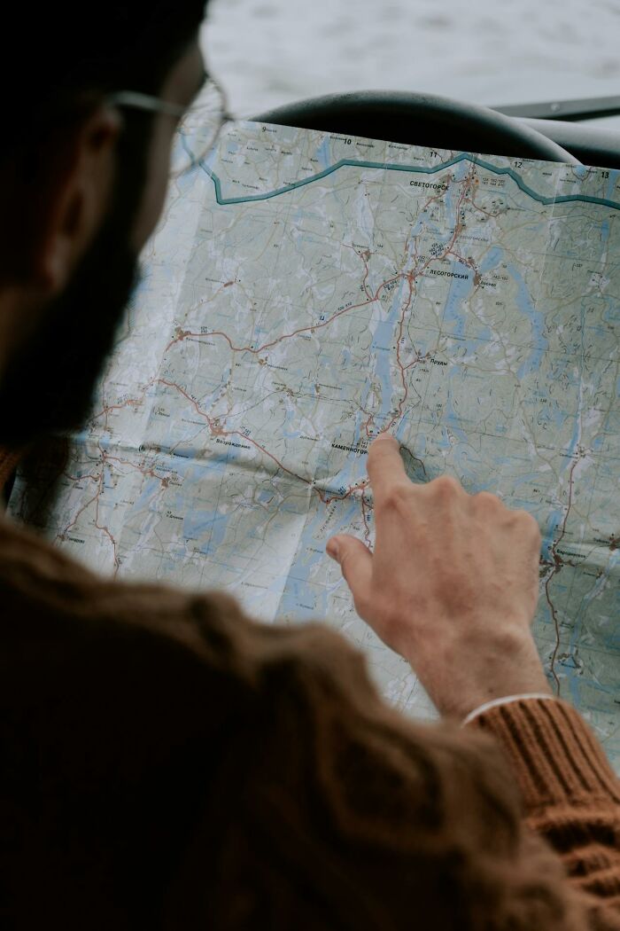 Person pointing at route on a folded map inside a car