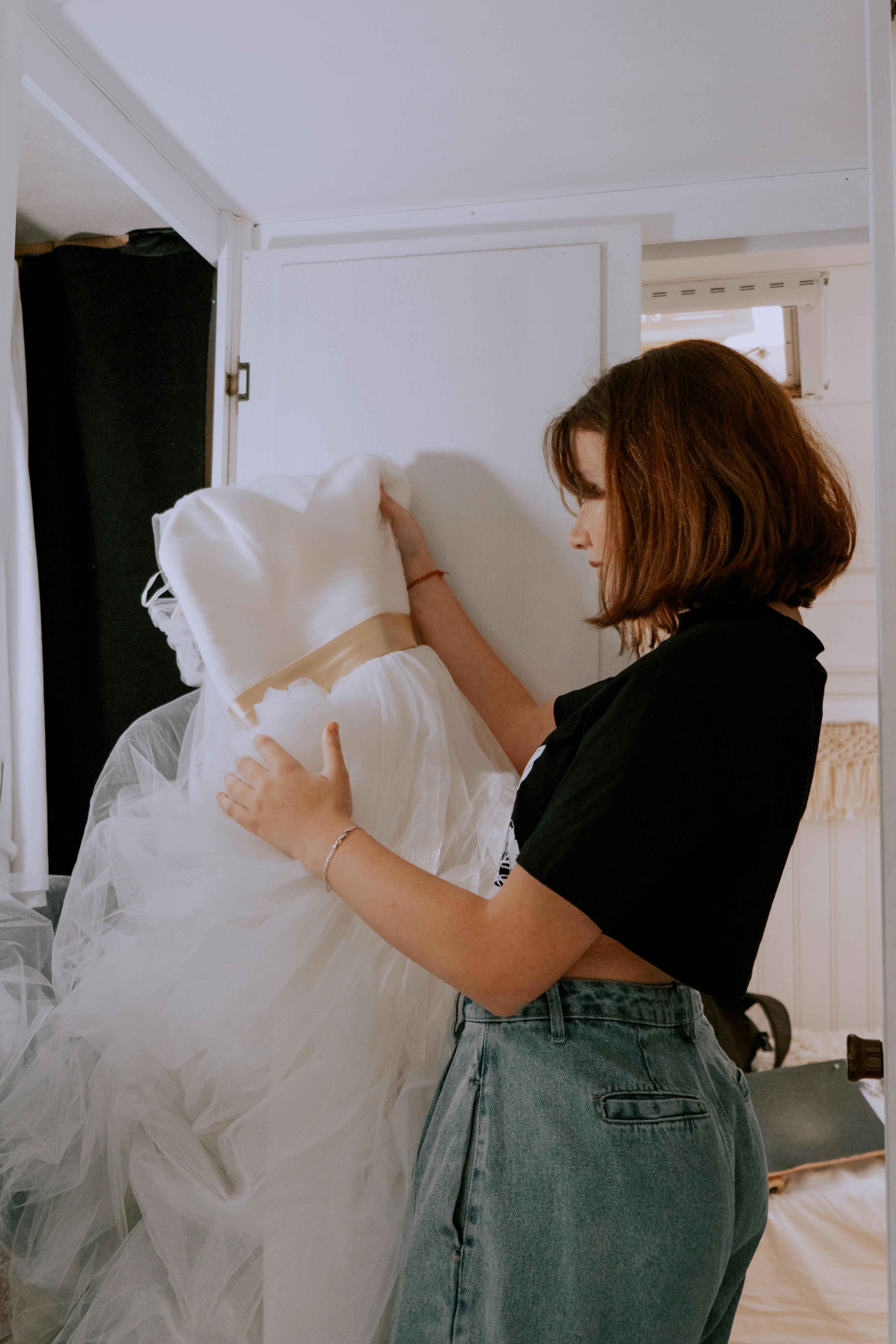 Woman holding a wedding dress indoors showcasing wedding dress