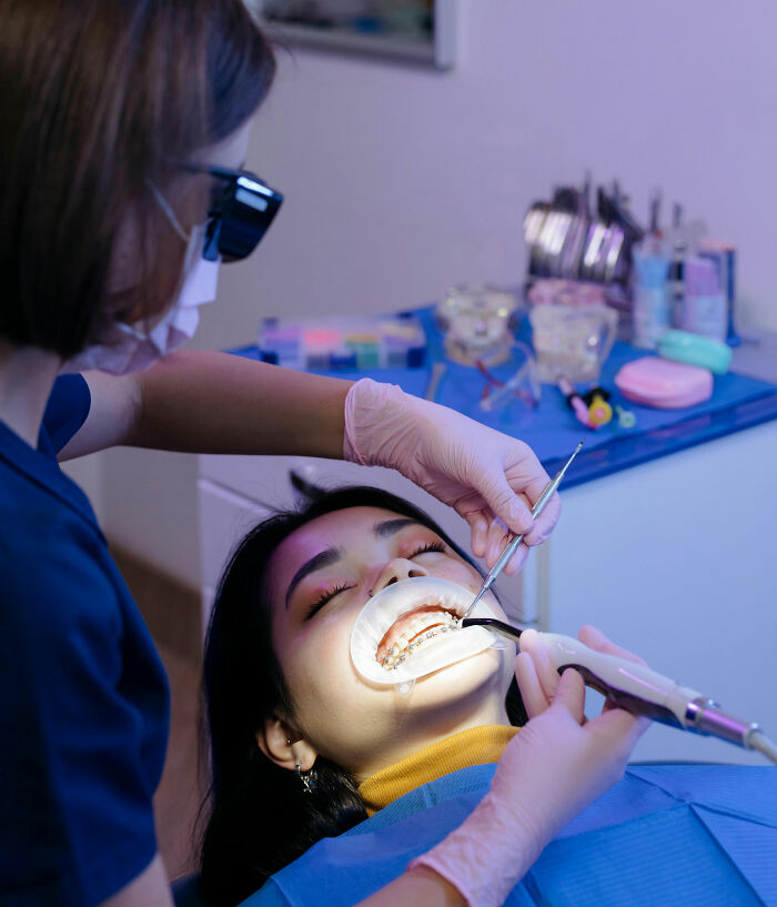 A woman in a dentist's chair having braces worked on, illustrating expensive habits that save you money.